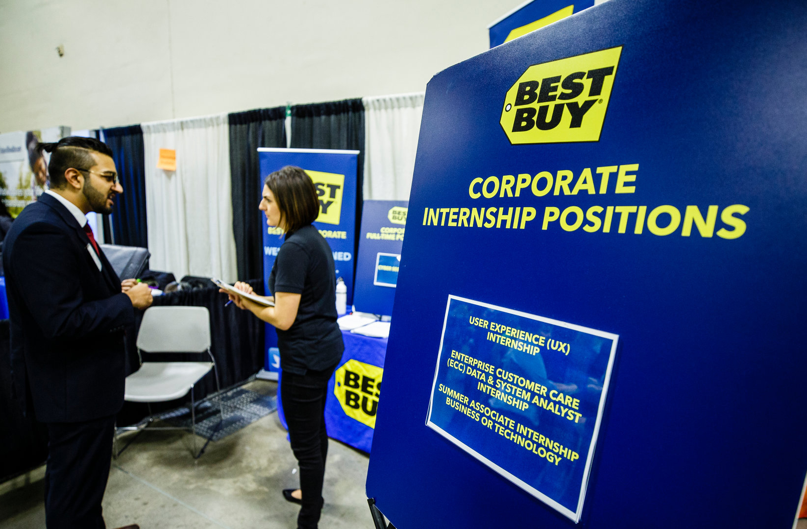 man and woman talking at a Best Buy booth at a job fair